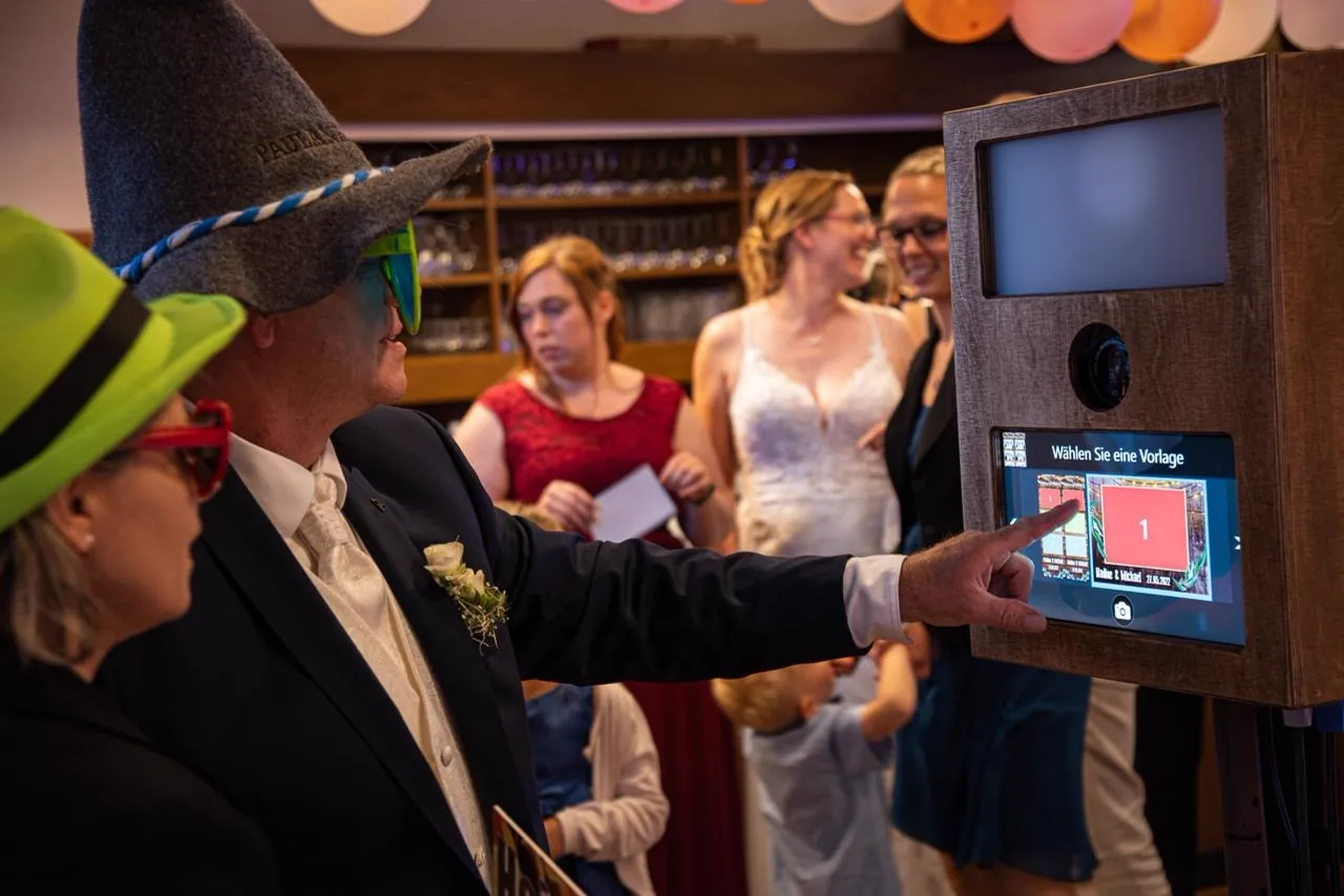 Wedding guests in playful hats and glasses using the open-air photo booth